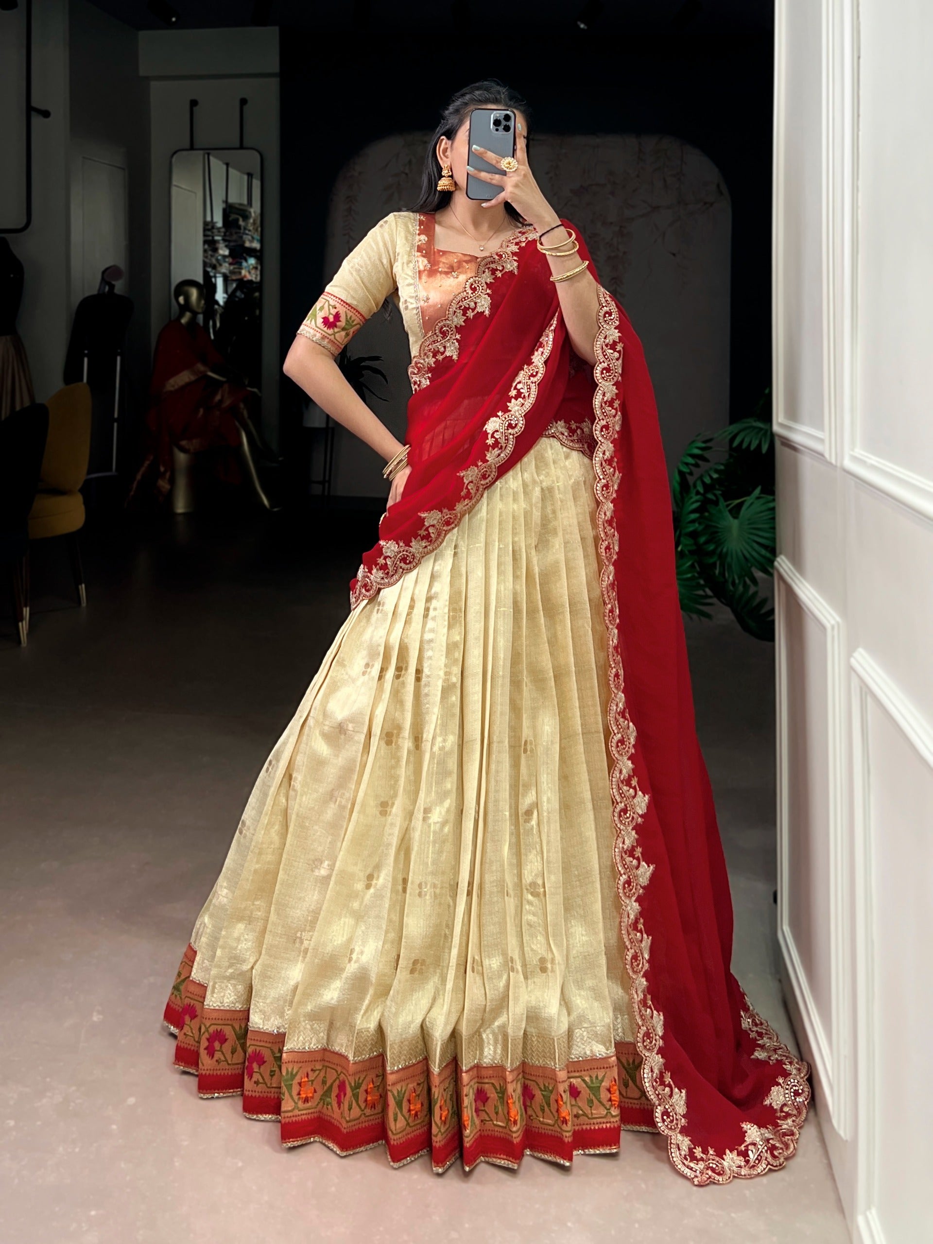Woman wearing a cream saree with red border and blouse