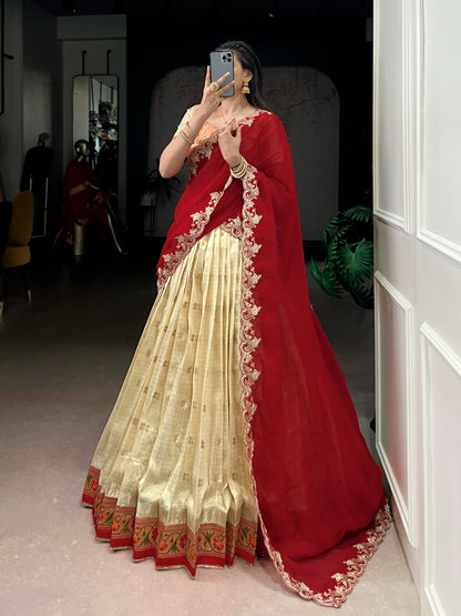 Person wearing a red and cream saree with intricate designs, 