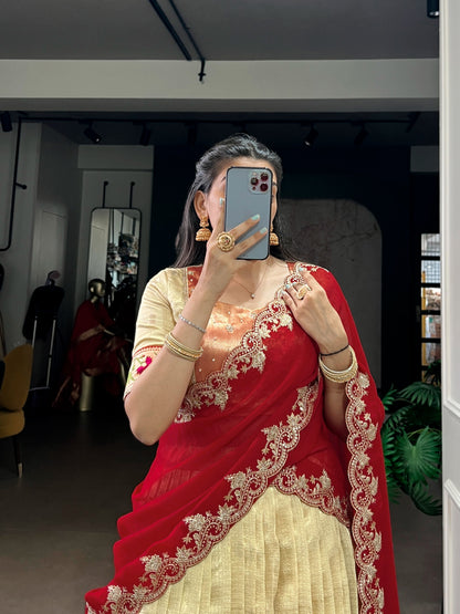 Woman in a red and gold saree taking a mirror selfie in a room.